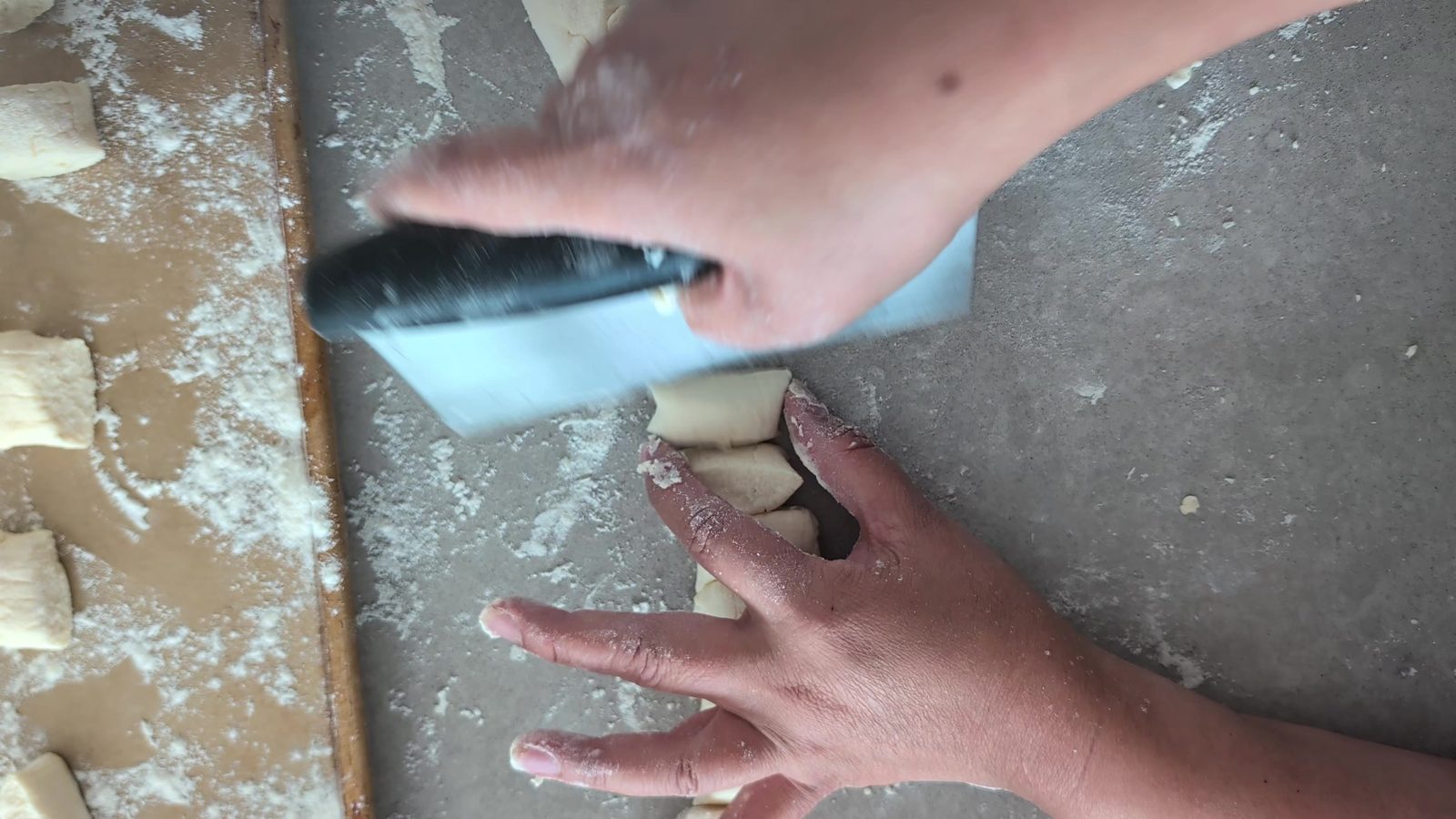 Cutting the ricotta gnocchi dough into pillows on a floured board
