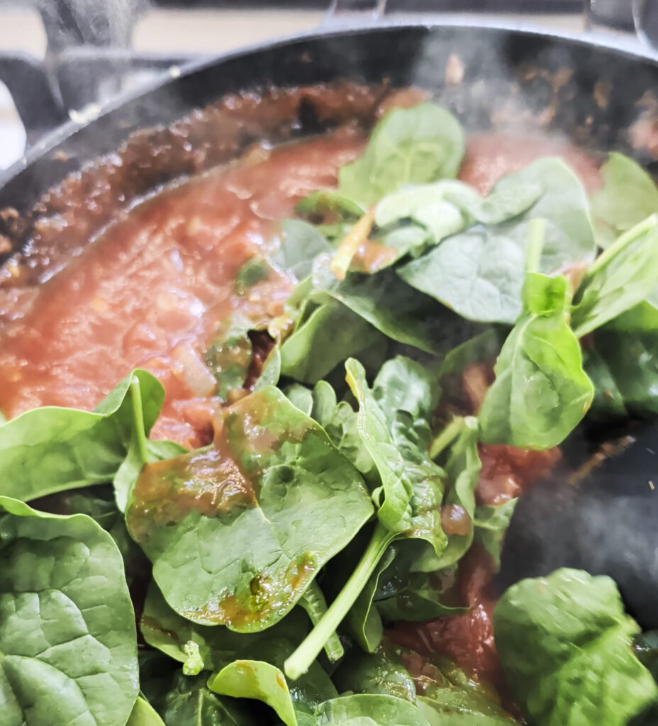 Baby spinach wilting into the tomato sauce